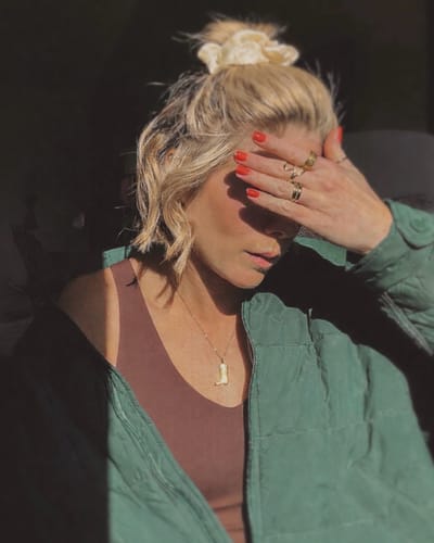 Reviewer wearing the gold Jessie Cowgirl Boot Pendant with a casual green jacket and brown top.