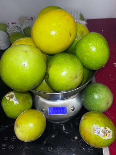 Ein Kunde wiegt die gelieferten gelben und grünen Bio-Maracujas auf einer Küchenwaage.