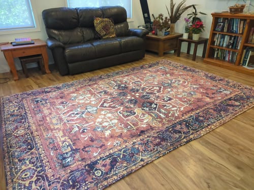 Reviewer's large Artemis print Mellow Mat laid out on the wooden floor of their living room.