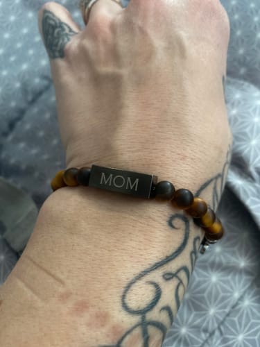 Reviewer wearing the Tiger Eye Bead Bracelet with its center bead engraved to say 'MOM'.