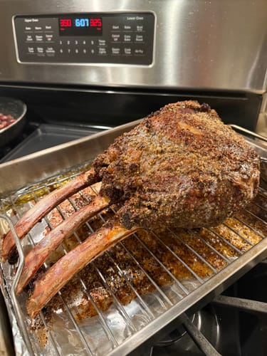 Customer's seasoned Tomahawk Prime Rib Roast resting on a wire rack after coming out of the oven.