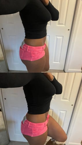 Reviewer's side view showing the fit of the pink MICRO MINI SHORTS with a black top.