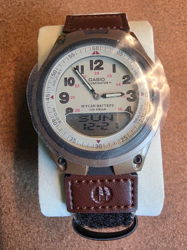 Foto de cliente del reloj Casio Análogo-Digital con esfera color crema y una correa de tela marrón.