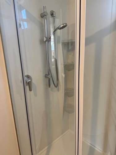 Reviewer's very clean glass shower door, looking transparent after using Bar Keepers Friend Cleanser.