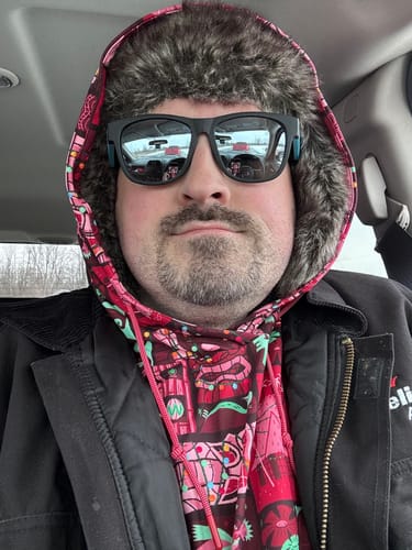 Customer wearing the colorful Mele Kalikimaka – Performance Hoodie under a black jacket and a furry hat.