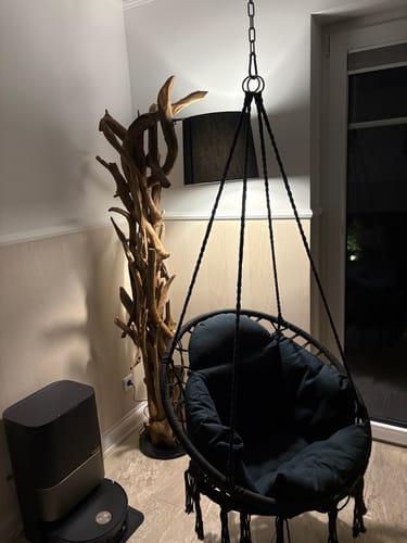 Ein Kunde zeigt die rustikale Wurzelholzlampe MORGAN, die beleuchtet in einer Ecke des Raumes steht.