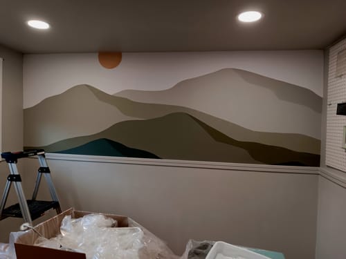 Customer's wall with the beautiful Ender Wallpaper, featuring a layered mountain mural in earthy tones with an orange sun.