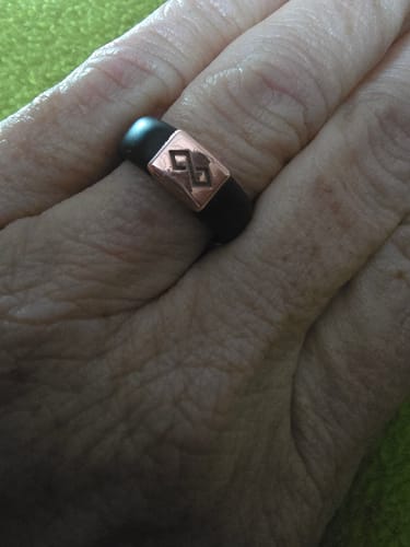 Close-up of a reviewer's hand wearing the black silicone MetalInfinity ring with a copper-colored metal element.