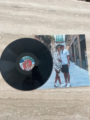 Customer's custom vinyl record with its personalized photo sleeve displayed together on a stone surface.