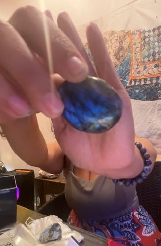 Customer holding a polished, iridescent labradorite crystal from their monthly subscription box.