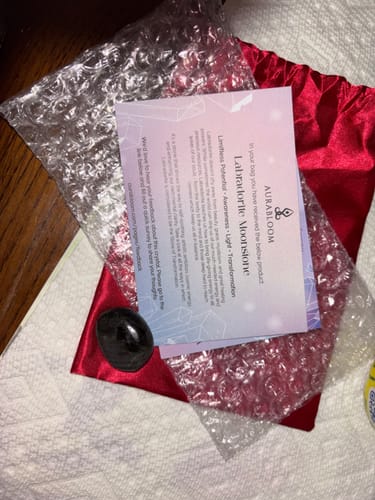 Customer's dark Labradorite Moonstone crystal from their monthly subscription, shown with its red pouch and info card.