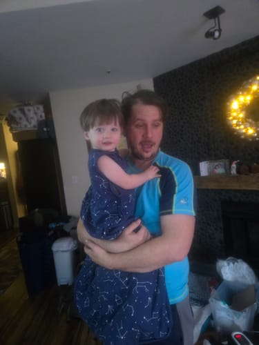 A customer holds a child wearing the navy blue Ultimate Baby Sleep Bag with a white constellation pattern.