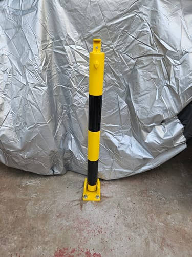 Customer's yellow and black 810 Fold Down Parking Post bolted upright onto a concrete floor.