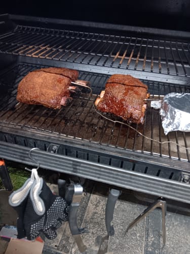 Customer's two large seasoned Bone-In Short Ribs cooking on a smoker grill.