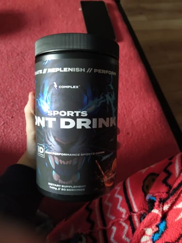 Customer's hand holding the black tub of Complex Iont Drink, showing the product label.