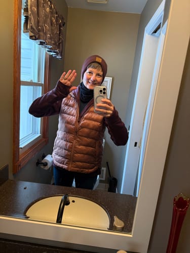 Reviewer taking a mirror selfie wearing the purple Cubby Hooded Sweatshirt layered under a vest and beanie.