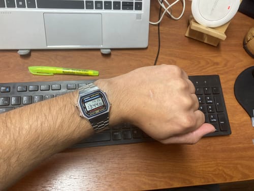 Reseñador usando su reloj Casio Vintage plateado en la muñeca mientras descansa la mano sobre un teclado.