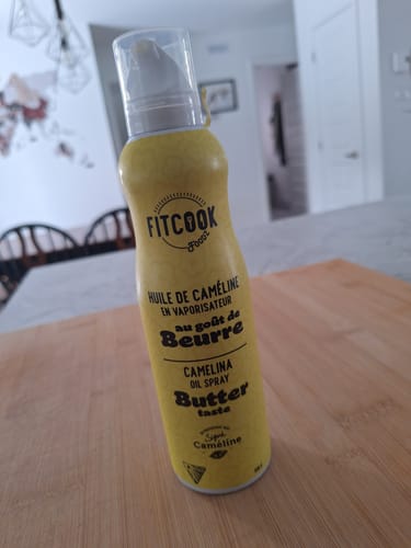 Photo d'un client de l'huile de caméline Fitcook au goût de beurre, posée sur une planche à découper en bois.