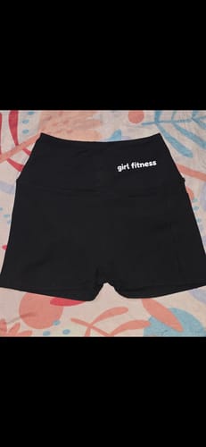 Customer's black, high-waisted sports shorts with 'girl fitness' text, laid out on a patterned surface.