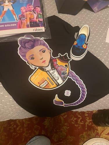 Customer's black kids t-shirt laid out, showing a colorful graphic print of a character.