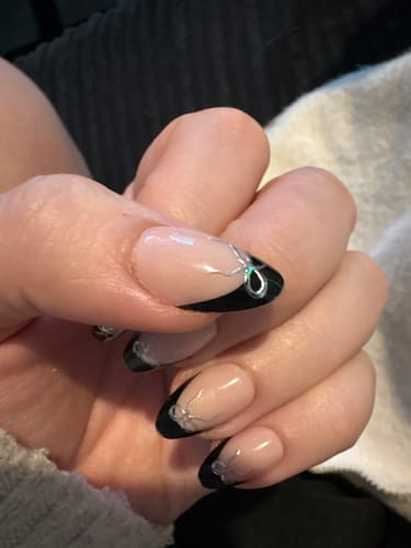 Close-up of a customer's hand wearing the Midnight Ribbon press-on nails, showing the black tip and silver ribbon design.