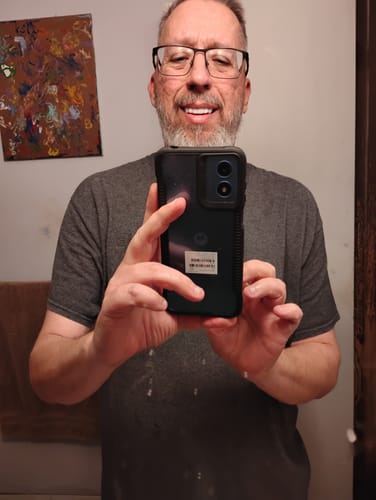 Customer smiling in a mirror selfie, showing off his custom Pop On Veneers.