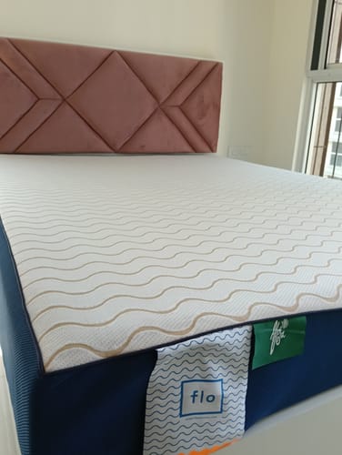Customer's Flo Mattress Ergo on a bed, showing the white patterned top, dark blue side, and a pink headboard.