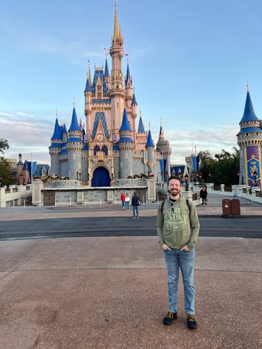 Reviewer wearing the green "Lake Destiny" Performance Hoodie while standing in front of Cinderella's Castle.