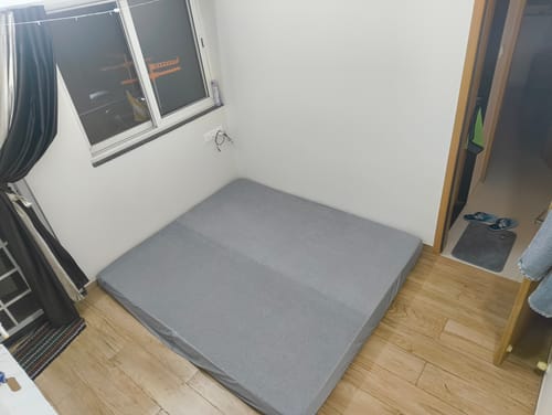 Customer's grey Flo mattress protector fitted on a mattress in a room with wood floors.