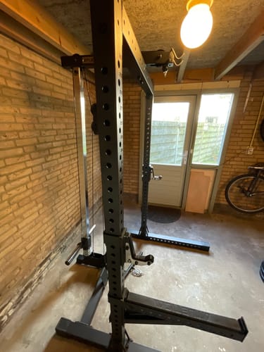 Ein Kunde zeigt sein stabiles schwarzes R7 Squat Rack, aufgebaut in einem Heim-Fitnessstudio.