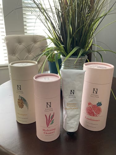 Reviewer's collection of Hanna Sillitoe products including conditioner, cleanser, and hand cream on a table.