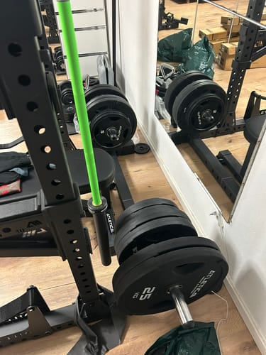 Rezensent zeigt das am Rack montierte R7 Plate Storage, beladen mit mehreren schwarzen Hantelscheiben.