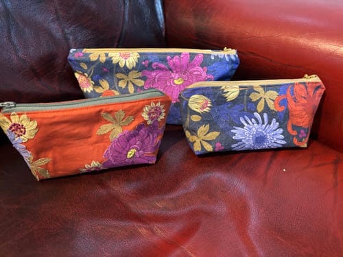 Customer's three floral zipped pouches made from the DIY bag bundle, shown sitting on a red leather surface.
