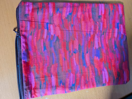 Customer's finished pouch made from the DIY bag bundle, showing the colorful abstract-patterned cotton fabric and a dark zipper.
