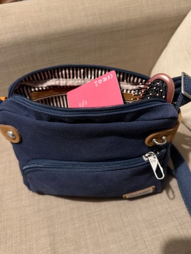 Customer's pink SPOTMINDERS Tracking Card placed inside an open blue canvas bag.
