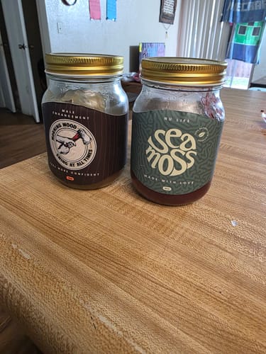 Customer's Morning Wood male enhancement jar sitting next to a Sea Moss jar on a wooden table.