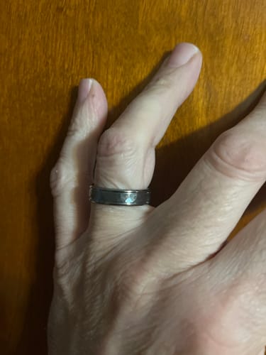 Customer's hand wearing the dark, hammered Atlas ring against a wooden surface.
