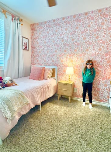Reviewer's photo of a child's bedroom with a statement wall of pink and orange floral Daisy Wallpaper.