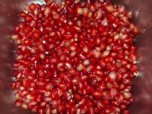 Rezensent zeigt eine Nahaufnahme der frischen, roten Kerne des Granatapfels.