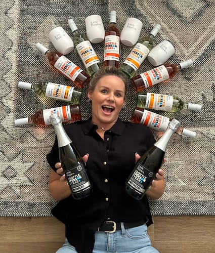 Reviewer on a rug, surrounded by a circle of Little Ripples wines, including Pinot Grigio, Rosé, and tumblers.