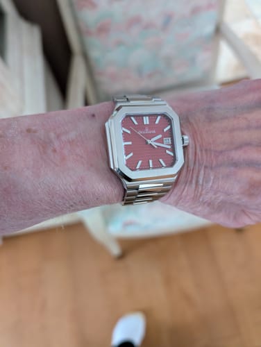 Reviewer wears the Oceaneva Tenuis watch on their wrist, showing its square burgundy dial and steel band.