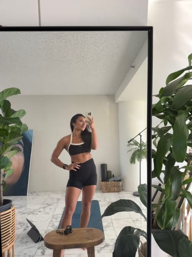 Customer taking a mirror selfie while wearing The Halter Bra in black and cream with matching shorts.