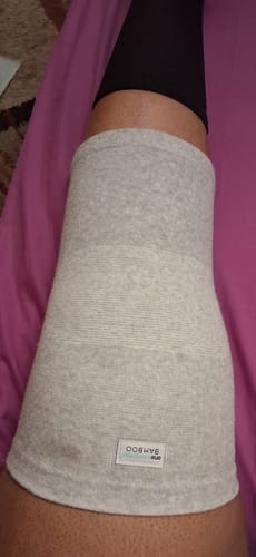 Close-up of a reviewer wearing the light grey Premium Bamboo Knee Sleeve on their leg while resting.
