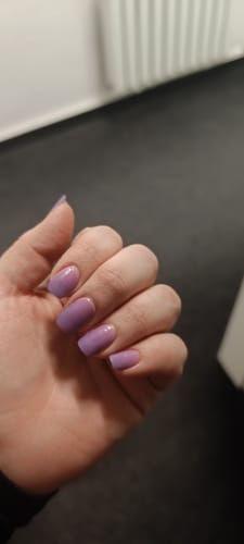 Hand einer Kundin mit aufgetragenen 'Dancing Till Dawn' UV-Gel-Nagelfolien mit rosa-lila Ombré-Farbverlauf.