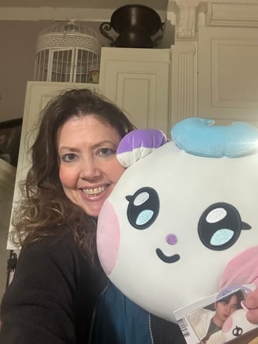 Customer smiling while holding the large MIGHTEEZ BIG FACE CUSHION and the included photocard.