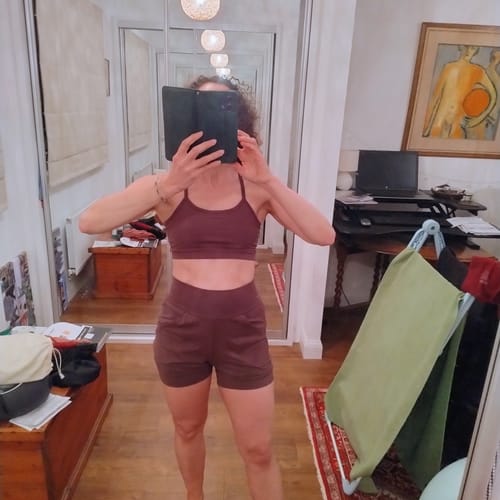 Reviewer taking a mirror selfie wearing the dark Slouchy Yoga Shorts and a matching sports bra.