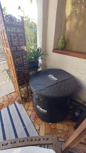 Customer's black Ice Pod, covered and set up on an outdoor brick patio.