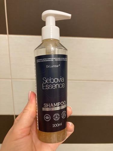 Vásárló kezében tartja a Sebovia Essence sampont egy csempézett fürdőszobában.