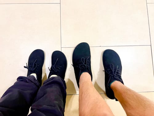 Two reviewers show off their matching black Muse Ⅰ - Barefoot Shoes from a top-down perspective.