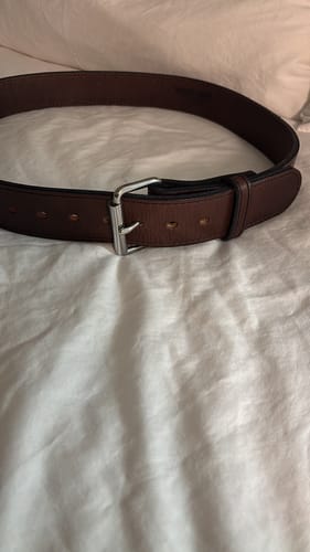 Customer's brown Xtreme belt with a silver roller buckle coiled on a white surface.